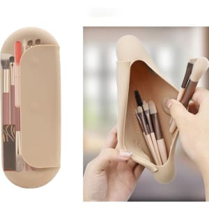 A beige silicone makeup brush holder with various brushes inside and a hand holding it. It has a minimalistic design.