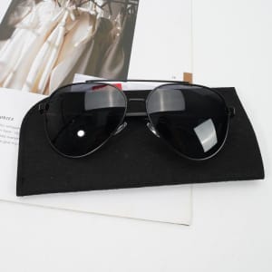 Polarised sunglasses with black lenses and a black felt storage bag, placed on a magazine.