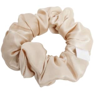 A custom satin scrunchie in a soft beige colour, featuring a simple design and a small tag.