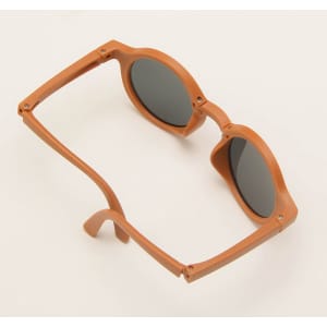 Foldable sunglasses in a warm brown colour with dark lenses, featuring a simple design and a logo.