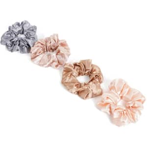 Four satin hair scrunchies in silver, beige, cream, and blush pink arranged in a row, featuring a logo.
