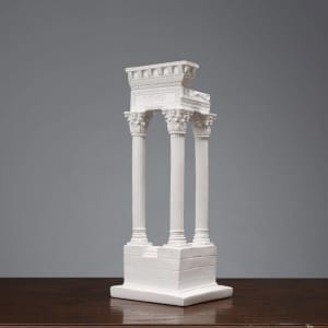 A white resin 3D model ornament featuring classical columns and a decorative arch, displayed on a wooden surface.