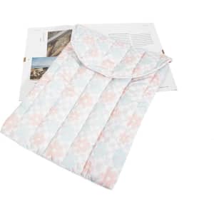 A puffy quilted tablet sleeve bag in pastel colours with a floral pattern, laid over a magazine.
