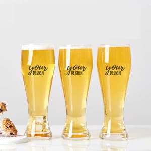 Three tall, clear pilsner glasses filled with golden beer, featuring a logo design on the front.