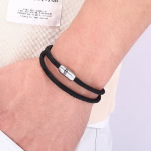 A double layer rope bracelet with a sleek black design and a silver magnetic clasp, worn on a wrist.