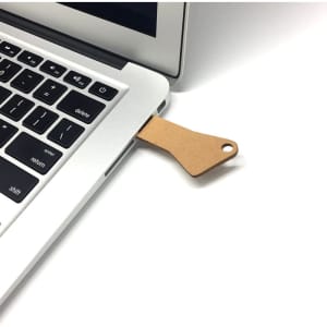 A biodegradable 4GB USB flash drive is connected to a laptop, featuring a brown, eco-friendly design.