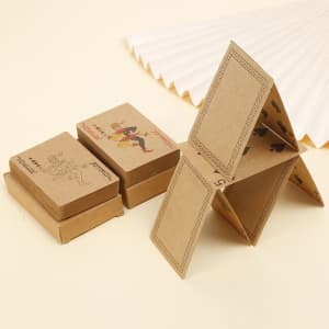 Kraft paper playing cards in brown packaging, featuring various designs, stacked and arranged in a house shape.