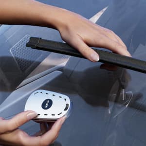 A car wiper repair kit in white, featuring a tool being applied to a windscreen wiper.