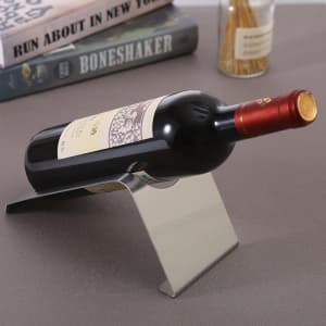 A drink bottle holder made of stainless steel, featuring a sleek design, holding a wine bottle at an angle.