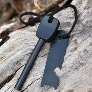 A black fire starter tool with a lanyard and metal scraper, resting on a wooden surface.