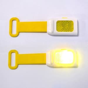 A yellow LED reflective bicycle light with a silicone strap, featuring a bright yellow illumination and textured surface.