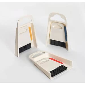 A table cleaning brush with dustpan set in white, featuring handles in yellow, red, and blue.