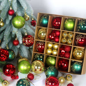 A set of 44 Christmas ornament balls in green, red, gold, and white, displayed in a box alongside a decorated tree.