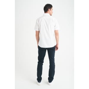 A man wearing a white short sleeve button-up shirt, standing with his back to the camera, paired with dark jeans.