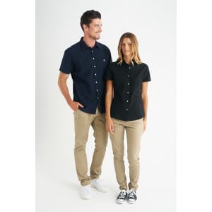 A black ladies short sleeve shirt is displayed on a model, paired with beige pants and sneakers, featuring a logo.