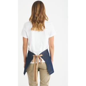 A short waist apron in denim with a tan tie, worn by a person facing away from the camera.