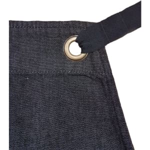 A dark denim bib apron featuring a metal grommet for adjustable ties. It includes a branding logo.