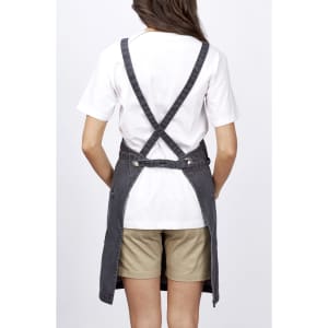 A grey bib apron worn over a white t-shirt, featuring crossed back straps and a casual fit.