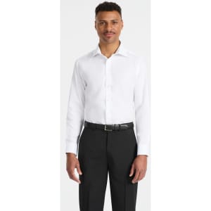 A man wearing a white button-up shirt with long sleeves and black trousers, featuring a logo on the shirt.
