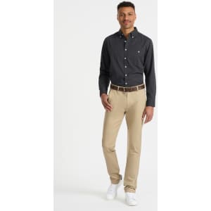 A man wearing a black shirt and beige Riley men's chino pants, accompanied by a belt and white shoes.