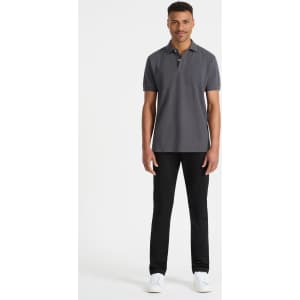 A grey men's polo shirt displayed on a model, paired with black trousers and white shoes. It features a logo.