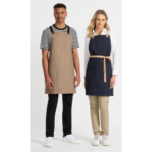 Two individuals wearing Brooklyn bib aprons; one in tan and the other in navy blue, with a logo displayed.
