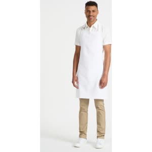 A man wearing a white bib apron stands against a plain background, showcasing the apron’s fit and style.