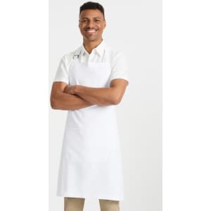 A man wearing a white short sleeve button-up shirt and a white apron, standing with arms crossed and smiling.