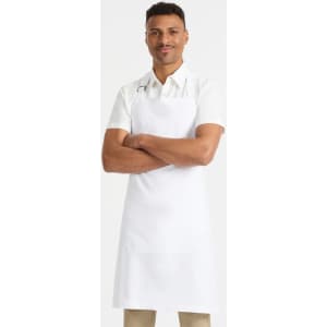 A man wearing a white bib apron stands with arms crossed, featuring a logo on the apron.