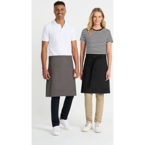 Two models wearing aprons, one in grey and the other in black, standing side by side. Both models are dressed in casual attire.