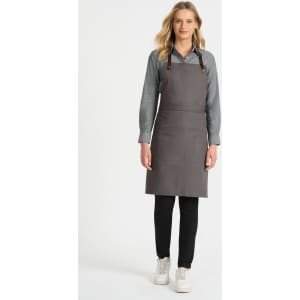 A grey bib apron with leather straps, worn over a grey shirt and black pants, featuring a front pocket.