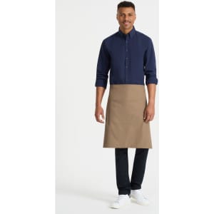 A man wearing a navy shirt and a beige waist apron with pockets, standing against a plain background.