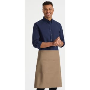 A man wearing a navy shirt and a beige waist apron with a front pocket. The apron features a branding logo.