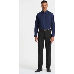 A man stands wearing a navy blue long sleeve button-up shirt and black trousers. The shirt has a logo.