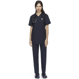 A woman wearing navy unisex scrub pants and a matching top, paired with a stethoscope. The outfit features pockets and a logo.