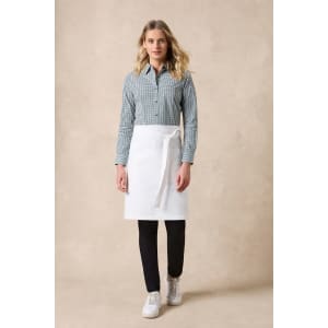 A woman is wearing a checkered long sleeve button-up shirt in green and white, paired with a white apron and black pants.
