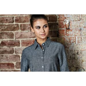 A grey button-up long sleeve shirt is displayed against a brick wall, featuring a collared neckline and button closure.