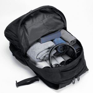 A black backpack with neatly arranged rolled clothes, a box, and a pair of headphones inside.