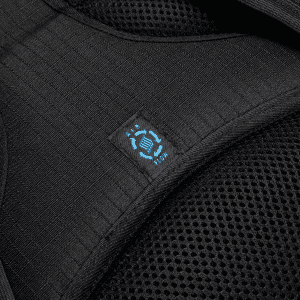 A close-up of a black backpack strap with mesh fabric and a blue logo.