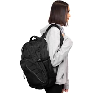 A black Fitzroy Backpack featuring multiple pockets and a mesh side compartment, worn by a person in a grey hoodie.
