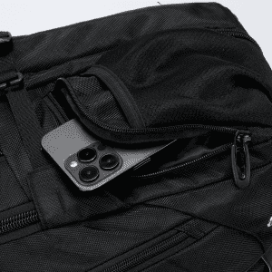 A black Eiger backpack with a smartphone tucked in a zippered pocket. The bag has a textured surface and features a logo.