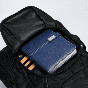 A black backpack with a zippered opening displaying a blue notebook and wooden items inside.