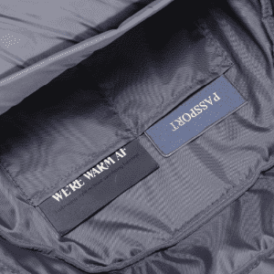Interior view of a grey backpack featuring compartments for a passport and other items, with a logo present.