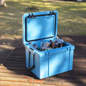 A blue 25L cooler box is filled with various soft drink bottles and water bottles, sitting on a wooden surface.