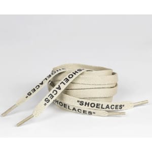 A pair of cream-coloured printed shoelaces with metal tips, featuring the word "SHOELACES."