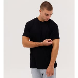 A black short-sleeve t-shirt is worn by a model adjusting the sleeve, set against a plain background.