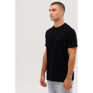 A black T-shirt displayed on a male model, paired with grey trousers. The T-shirt features no visible logos.