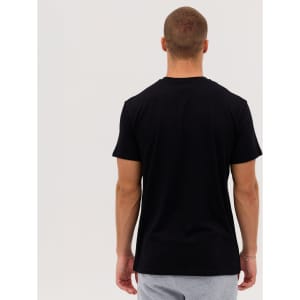 A man wearing a black Everyday Tee, viewed from the back, with grey shorts. The tee has a logo on it.