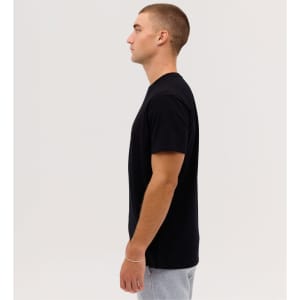 A plain black T-shirt on a male model shown in profile against a neutral background. It has a logo on the sleeve.