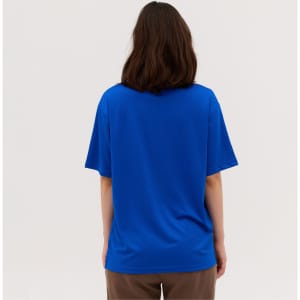 A blue tee shirt viewed from the back, featuring short sleeves and a relaxed fit. It has a logo on the back.
